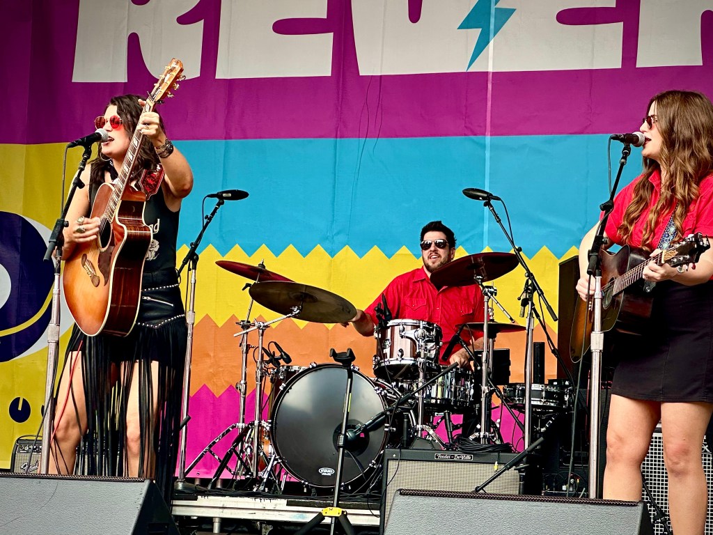 Mae Estest with guitar player and drummer at CMA Fest 2025 in Nashville Tennessee