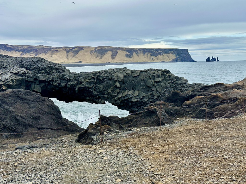 View of ocean and cliffs including Reynisdrangar in the distance