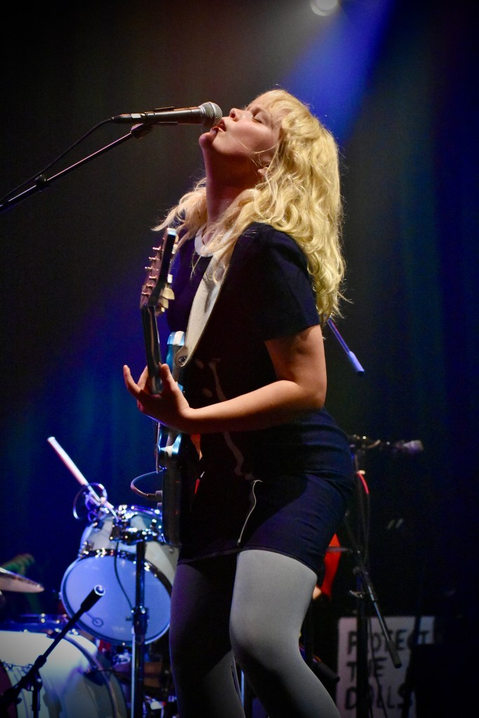 Kenzie from Girl Tones singing and playing guitar while performing in Nashville at Brooklyn Bowl