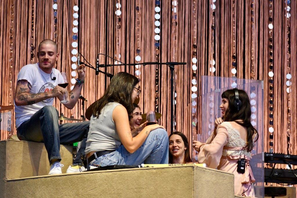 Clairo on stage with band drinking wine before performance at Hinterland Music Festival