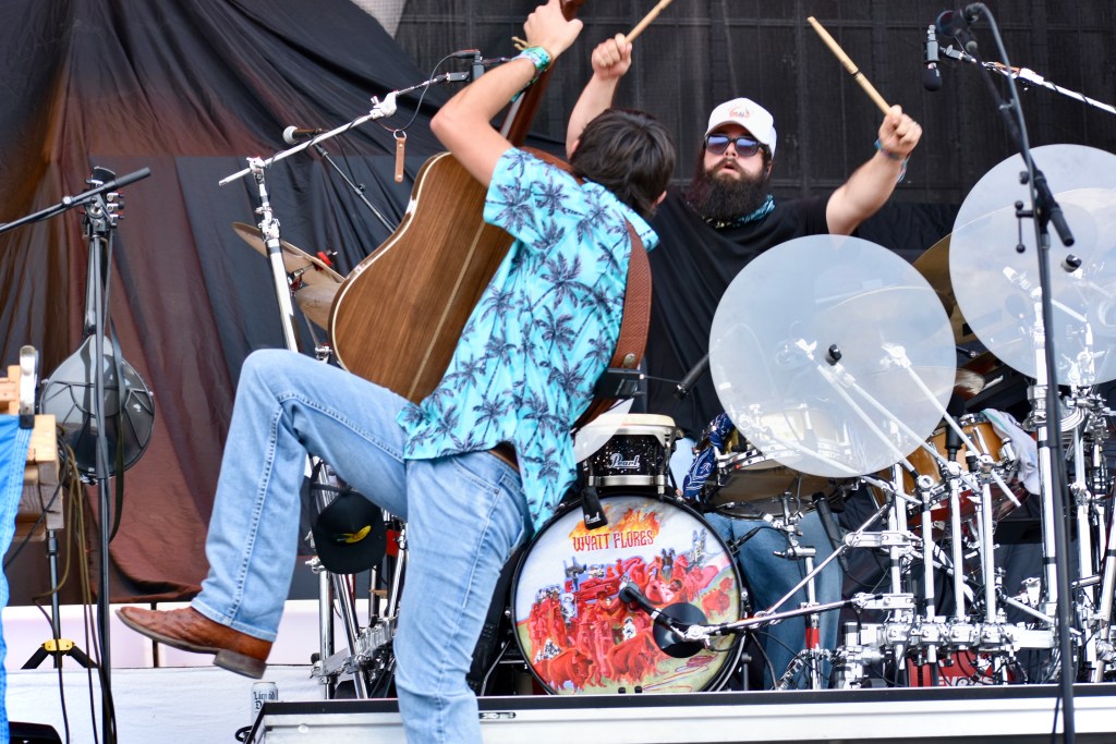 Wyatt Flores playing guitar and Jake Lynn on drums in background at Hinterland 2025